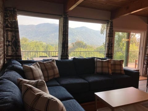 Relax in the cozy living room with an oversized sofa & fantastic views across the landscape. Large windows invite natural light, creating a warm atmosphere perfect for unwinding, reading, or enjoying time with loved ones while soaking in the scenery.