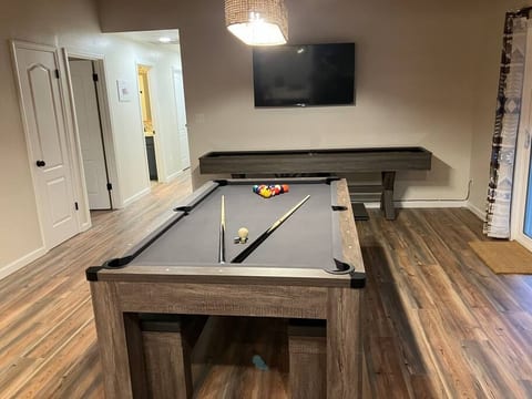 Enjoy a second game room featuring a pool table that also converts to a ping pong table and a shuffleboard table. Ideal for friendly competition and relaxation, this stylish space offers a fun atmosphere for guests to enjoy.