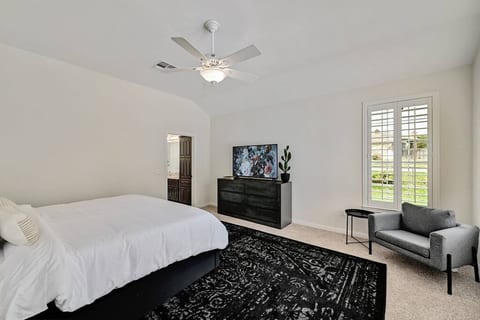 Primary bedroom with large smart TV and ensuite bathroom with shower and bathtub.