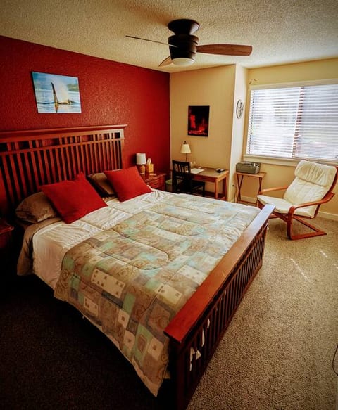 Queen bed with memory foam mattress, small writing desk and a comfortable chair.