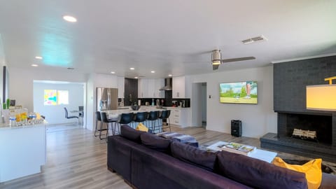 Large living room with a 60" smart TV and Karaoke bluetooth speaker opening to the kitchen and island with seating for 6
