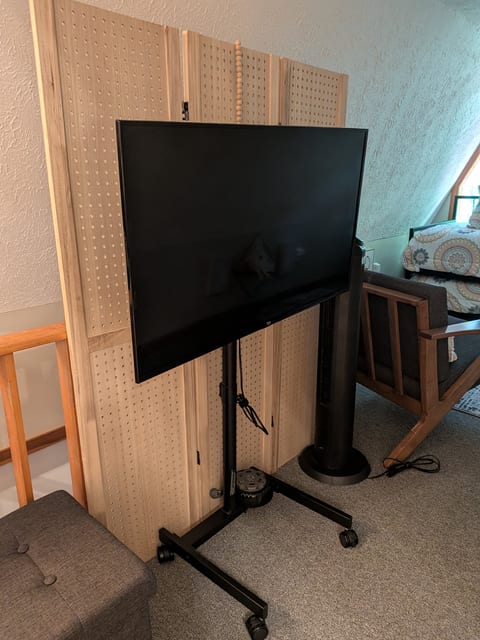 Large smart TV on movable stand in a cozy loft-style living area