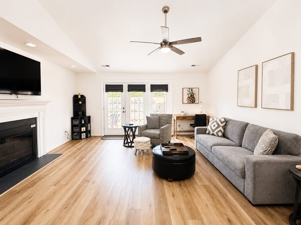 Large living room with 65” smart TV. Open floor plan with dining room. Dedicated workstation with comfy chair and easily accessible power.