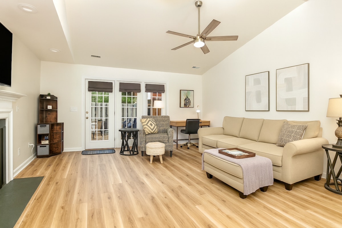 Large living room with 65” smart TV. Open floor plan with dining room. Dedicated workstation with comfy chair and easily accessible power.