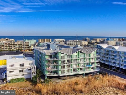 Arial view showing the north and west sides of the condo building, the pool and the Atlantic Ocean.
