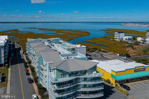 Arial view showing the east and south side of the condo building, the pool, parking overflow parking on 76th St. and the building's proximity to the Assawoman Bay.