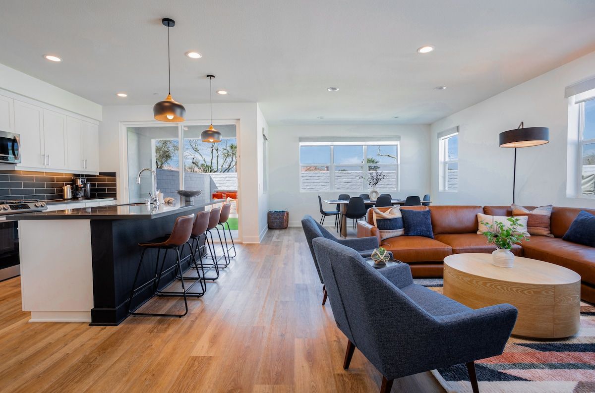 The spacious living room features an open space concept with stunning mountain views, modern, comfortable furnishings, a cozy fireplace as the centerpiece, and a 65" smart TV with a surround system for enhanced entertainment.