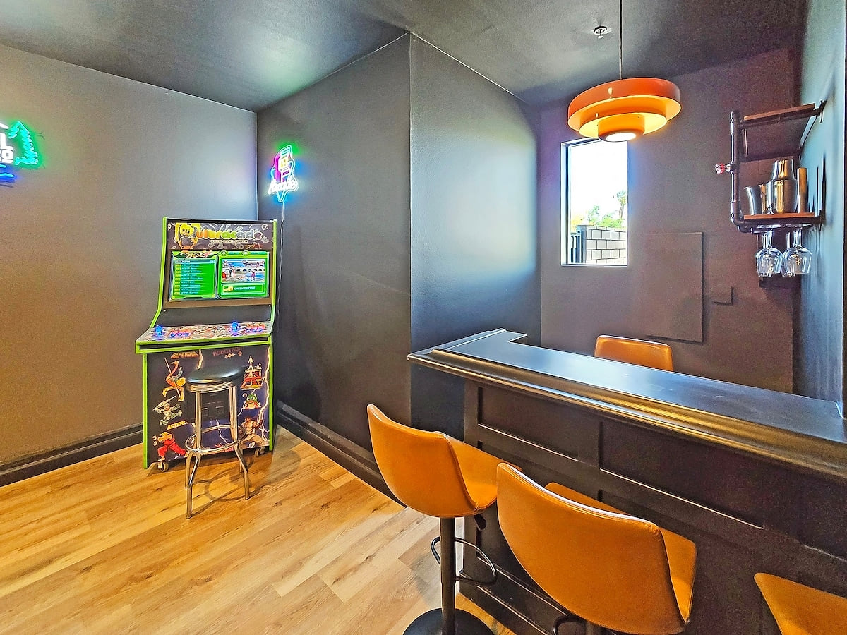 A sleek and sophisticated game room with a pool table, TV, and arcade—perfect for endless entertainment.