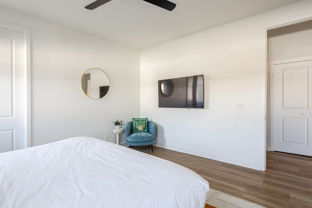 The bright first-floor bedroom emanates charm with its king-sized bed, a 55" smart TV, and a premium, comfortable mattress. This room also has a walk-in closet and a seating area.