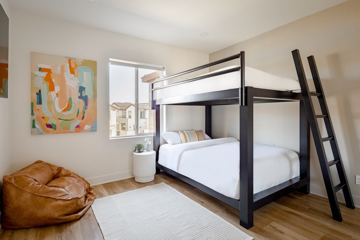 The queen-over-queen bunk bed offers a stylish blend of sophistication and modern design, featuring comfortable queen mattresses suitable for adults and kids alike. The room has a large closet, darkening curtains, and a 55" smart TV for added luxury.