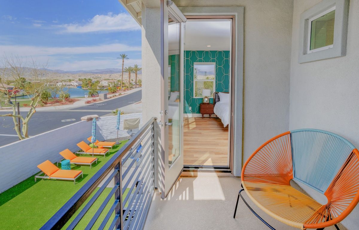 The private master bedroom balcony offers stunning views of a tranquil lake and the desert's mountains.