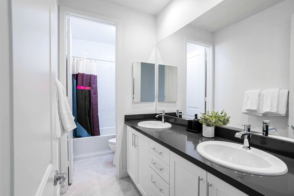 This second-floor bathroom features dual sinks and a separate shower area with a door, providing added privacy and comfort.