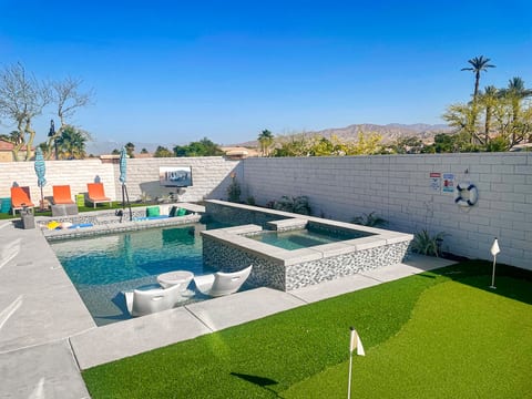 The spacious backyard offers amazing mountain and lake views. It includes a spa, saltwater pool, mini golf course, outdoor dining area, BBQ with seating, fireplace, outdoor TV, and toys for kids. It is perfect for relaxation and entertainment.