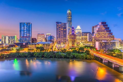 Night Skyline- vibrant show modern skyscrapers illuminated against the dark sky. Iconic buildings like Austonian & Frost Bank Tower shine brightly, reflecting off Lady Bird Lake. Cityscape blends urban sophistication w/lively energy of downtown.