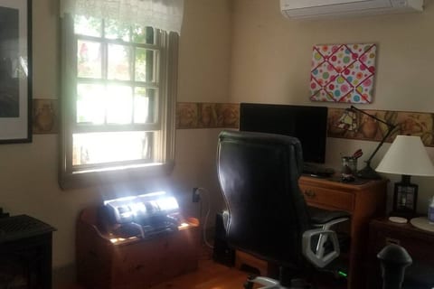Room has a desk with computer, printer and heat pump that provides AC in summer