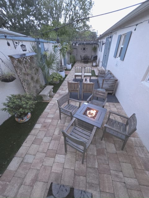 Overall View of Private Courtyard with Dining Area, Living Area, Fire Table and Fountain all spread throughout a 9 foot walled courtyard with lush plants and interesting decor.