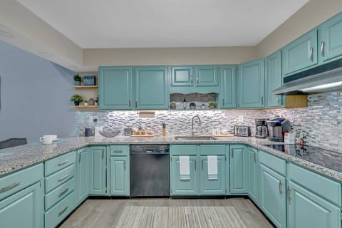Indulge in the elegance of this kitchen featuring captivating blue cabinets and a sophisticated silver dishwasher.