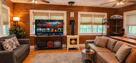 Cozy wood-paneled lounge with fireplace, large TV, and comfy seating