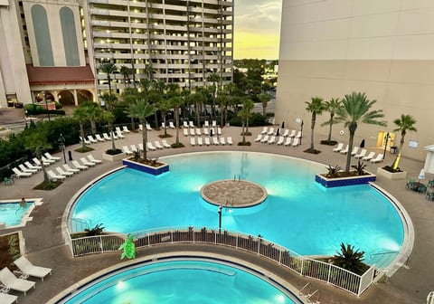 Resort-style lagoon pool surrounded by palm trees, lounge chairs, and plenty of space to relax.