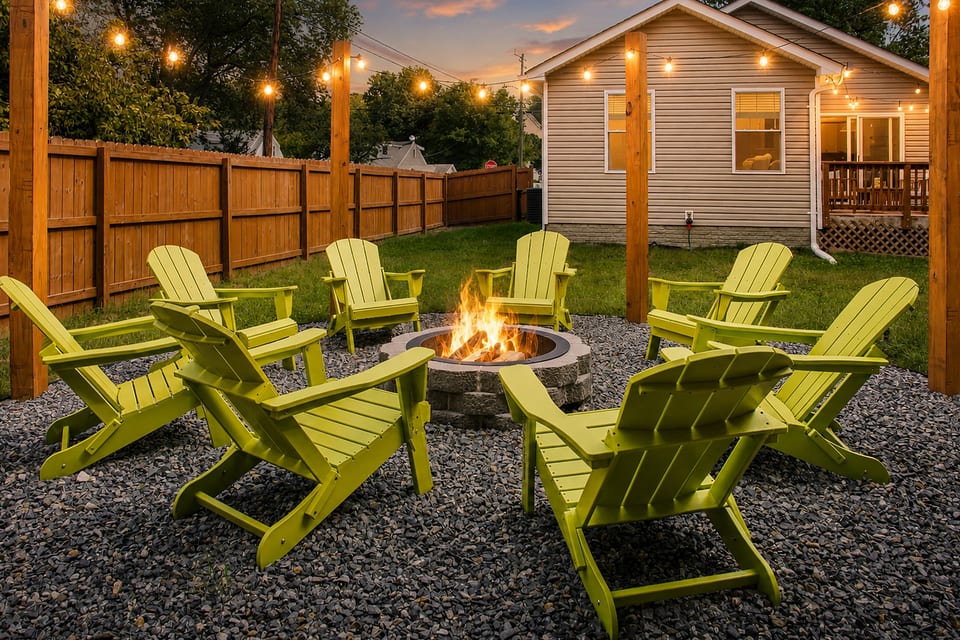 Cozy fenced backyard with fire pit, string lights, and Adirondack seating