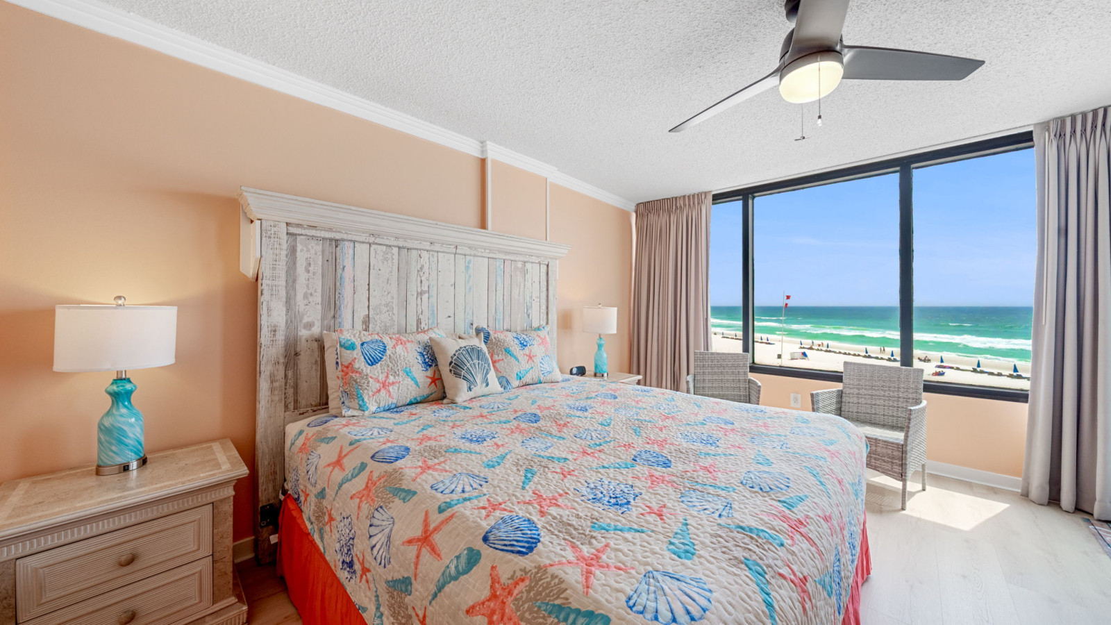 Beachfront bedroom with coastal décor, king bed, and floor-to-ceiling windows showcasing stunning Gulf views.