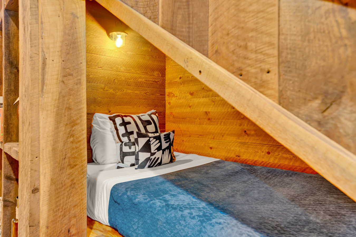 Discover this cozy bed tucked under the stairs, complete with a soft light to create the perfect atmosphere for rest and relaxation.