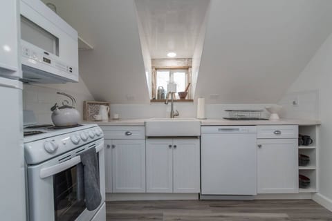 Unveil a small, yet comprehensively outfitted kitchen space, perfectly suited for the culinary enthusiast, providing all the necessary tools and amenities to effortlessly prepare and savor complete, gourmet meals.
