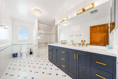 Elegant bathroom featuring a double vanity with gold accents, a soaking tub, and a glass-enclosed shower. The chic tile flooring and modern lighting add a touch of luxury, creating a bright and inviting space.