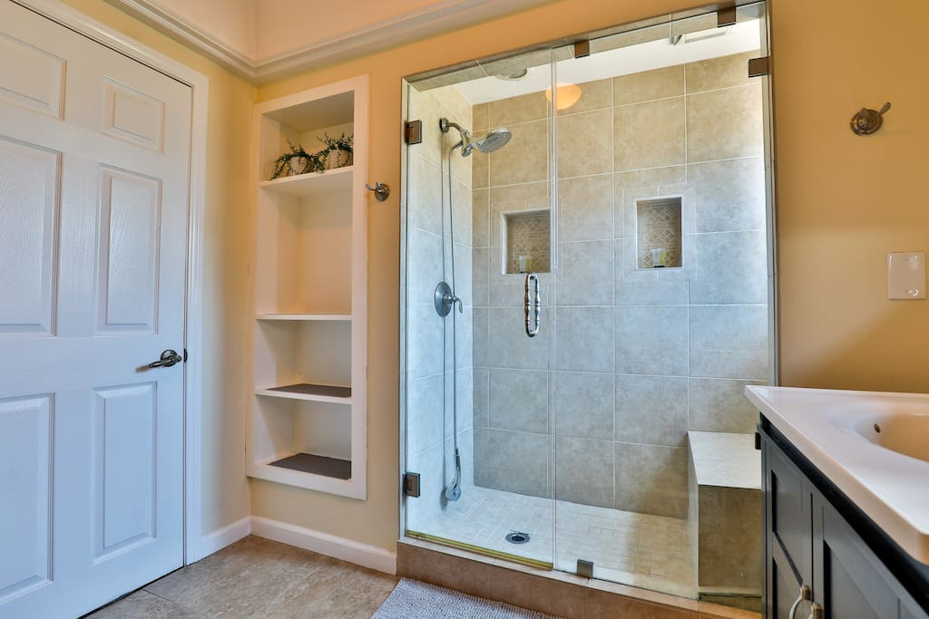 An efficient and well-lit bathroom, with a generously sized shower thoughtfully crafted to maximize guest comfort.