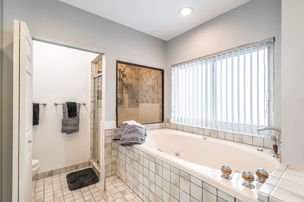 This bathroom is all about the little details. The patterned tile floor, the unique pendant light, and the framed artwork on the wall add personality and style. The lush greenery adds a touch of life and freshness.