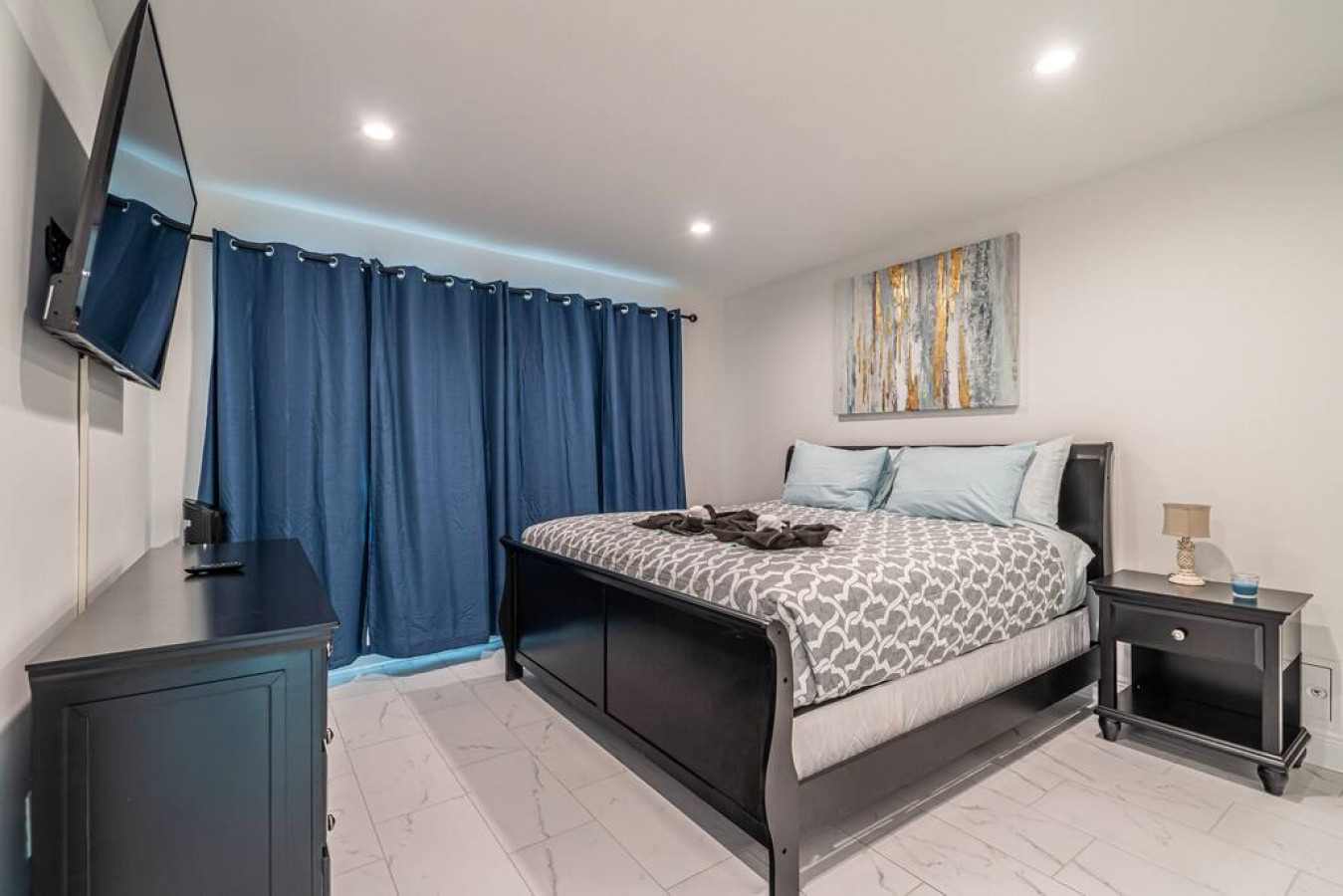 Imagine yourself sinking into the soft bed in this cozy bedroom, surrounded by fluffy pillows and warm lighting. The bed is like a cloud, inviting you to drift off into a peaceful sleep.