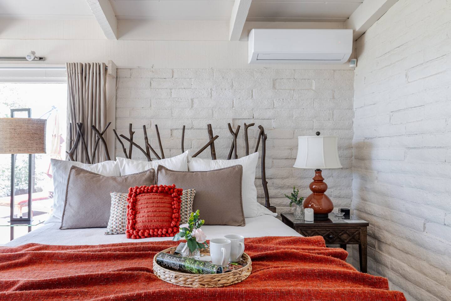 Wake to soft light spilling across the bed, a tray with fresh coffee waiting atop the warm orange throw. Step outside to the deck, then return to sink into pillows and linger a little longer—morning feels unrushed, private, and entirely yours.