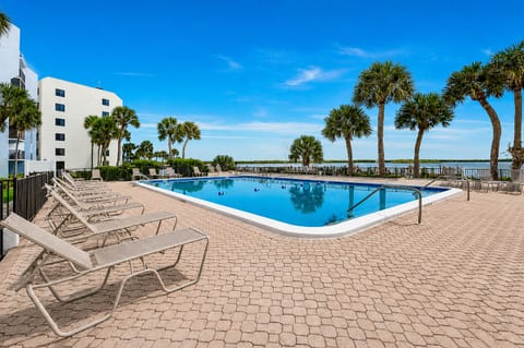 Resort-style pool with palm trees, loungers, and peaceful waterfront views