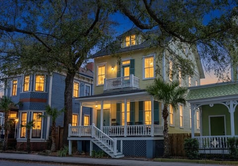 Charming historic home with glowing porch, balcony, and tree-lined curb appeal