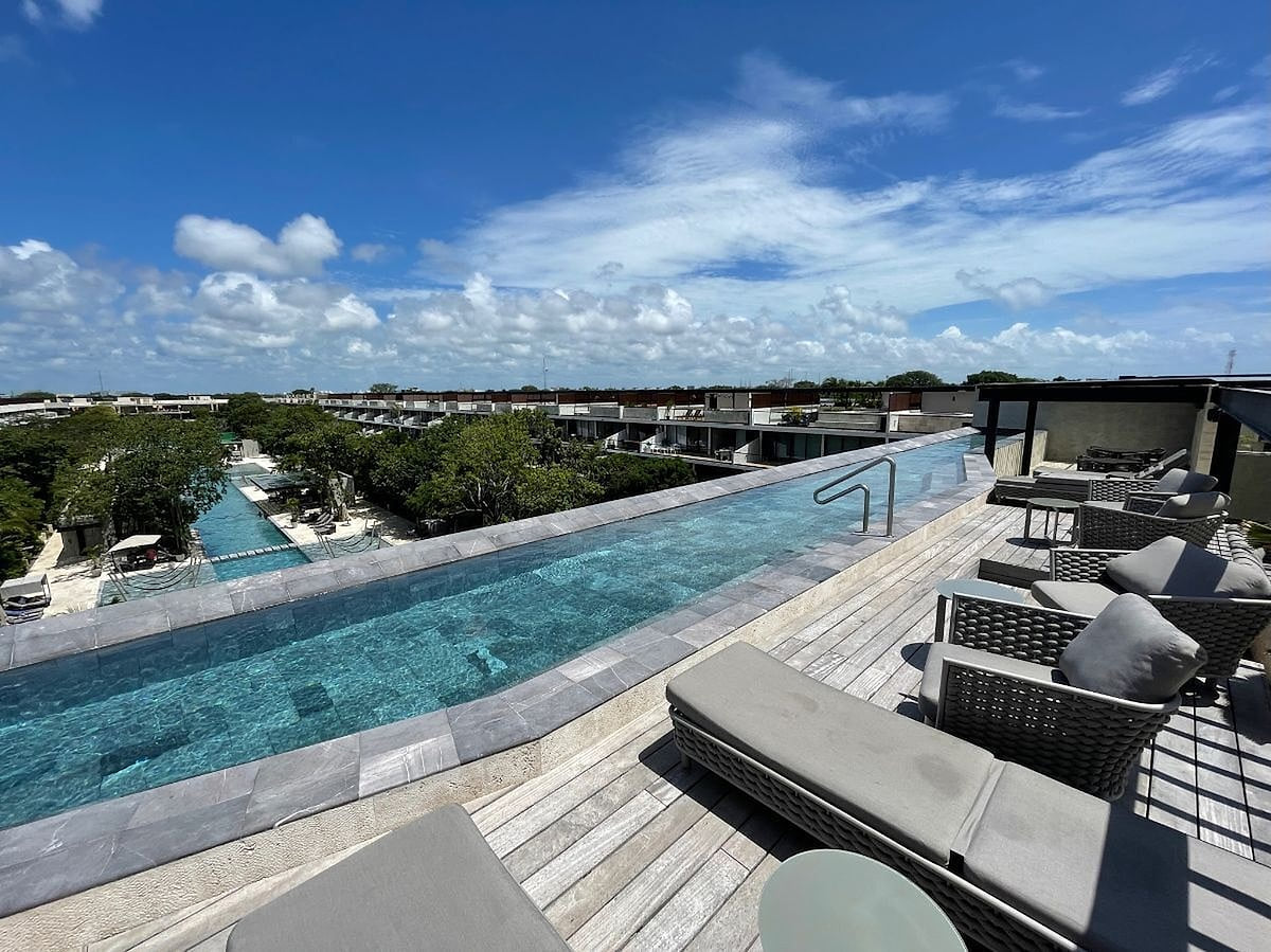 Panoramic adults-only rooftop infinity pool in the common area at AWA Playacar, offering expansive jungle views and a peaceful luxury setting near the beach.