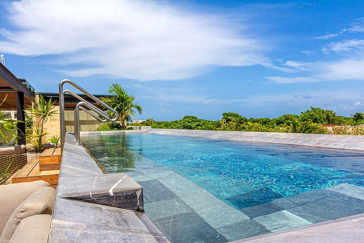 Long-view adults-only rooftop infinity pool in the common area at AWA Playacar, highlighting modern design, tranquil surroundings, and resort-style comfort.