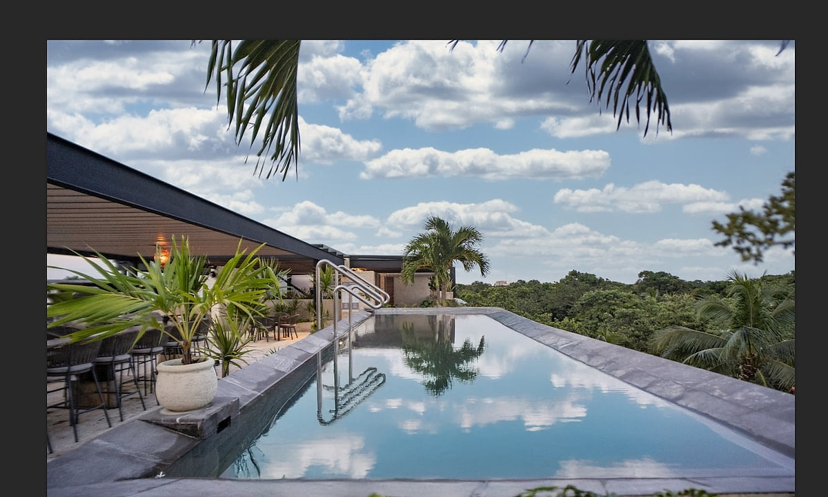 Rooftop infinity pool with panoramic views at AWA Playacar penthouse in Playa del Carmen, offering a luxury resort-style escape surrounded by lush jungle and open skies.