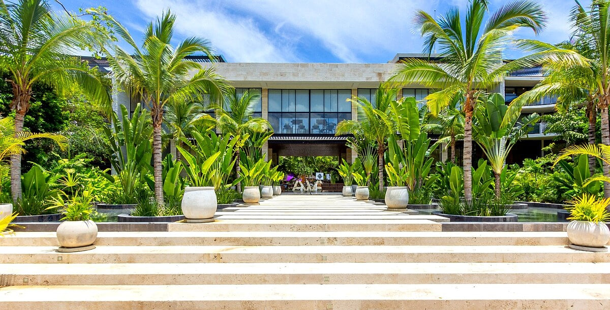 Elegant palm-lined entrance at AWA Playacar, welcoming guests to a luxury resort-style community in Playa del Carmen