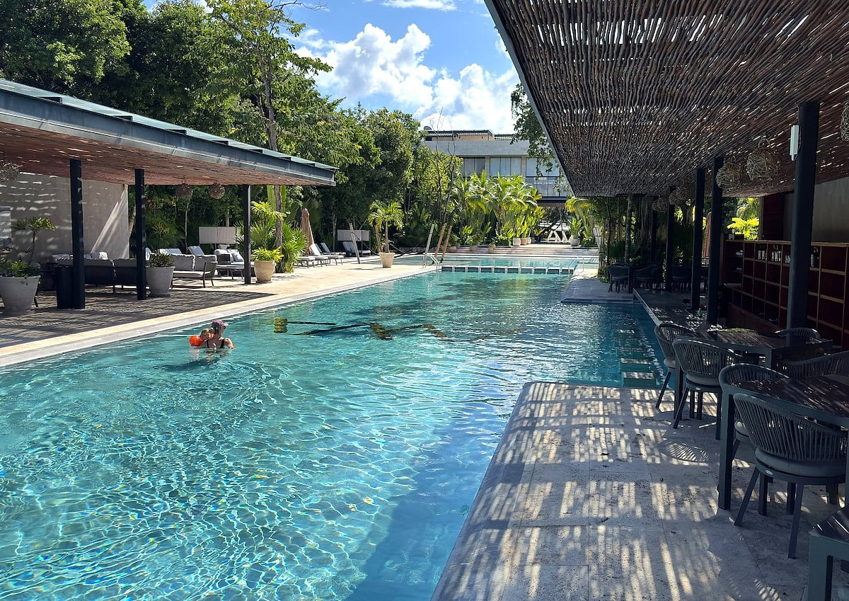 Shaded pergola, Bar and poolside seating at AWA Playacar, perfect for relaxing pool days in Playa del Carmen