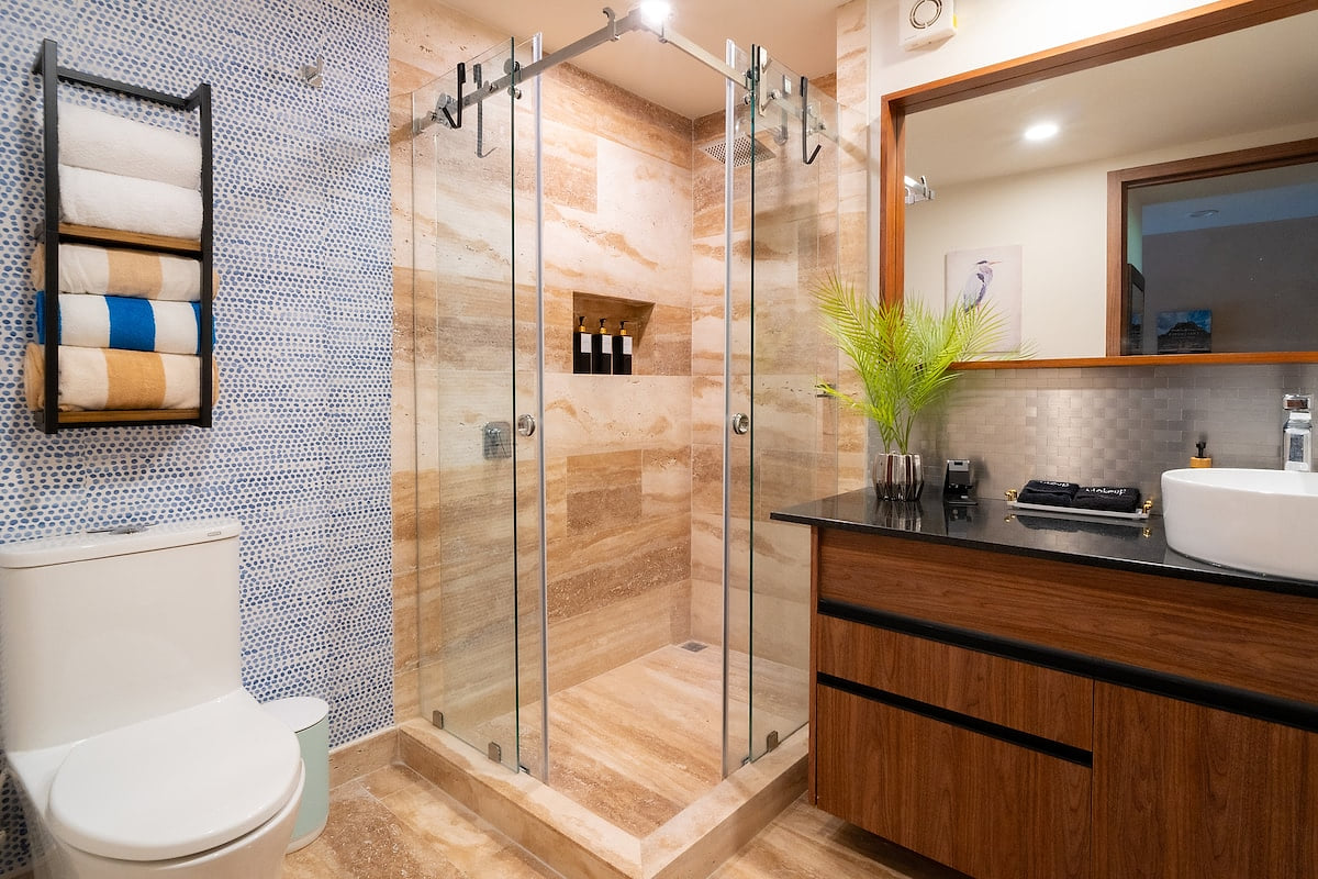 Enjoy the convenience of a built-in shelf for your toiletries and a sleek vanity area with a large mirror, perfect for your daily routine. The warm lighting and tasteful decor add to the tranquil ambiance of this private retreat.