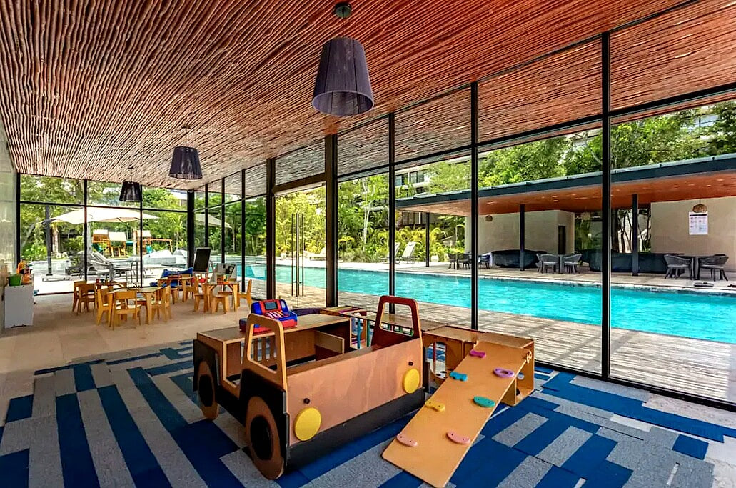 Covered family play area overlooking the pool at AWA Playacar, combining resort amenities with kid-friendly shared spaces for a comfortable family stay
