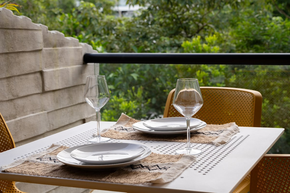 Start your day with a serene breakfast on this cozy balcony, featuring a well-laid table for two and lush greenery views. Perfect for a peaceful urban retreat, this private outdoor space offers a tranquil escape in the heart of Playacar.”