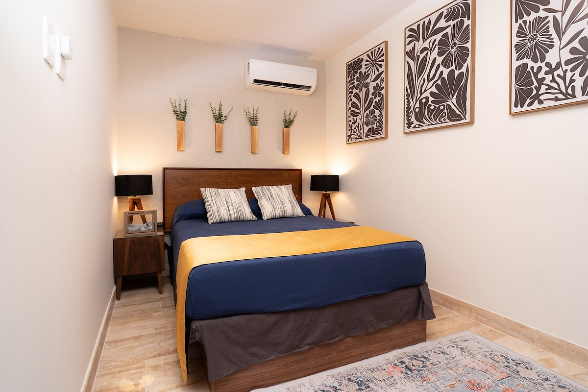 This intimate retreat boasts a plush double bed, adorned with a rich blue comforter and vibrant yellow accent blanket.  NOTE: the door is slatted and not totally private. 