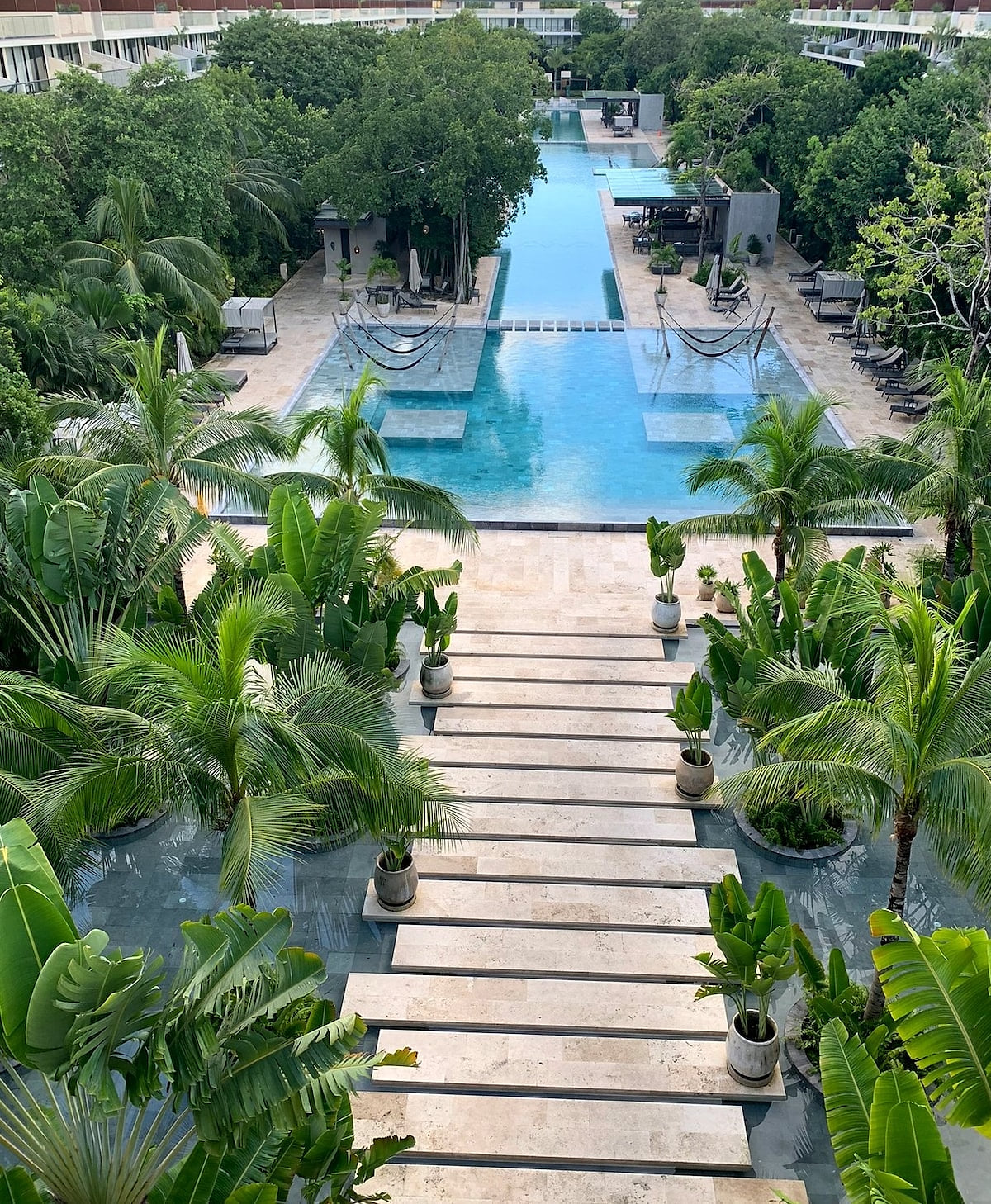 Crystal-clear resort pool with modern symmetry at AWA Playacar, offering a peaceful escape in Playa del Carmen