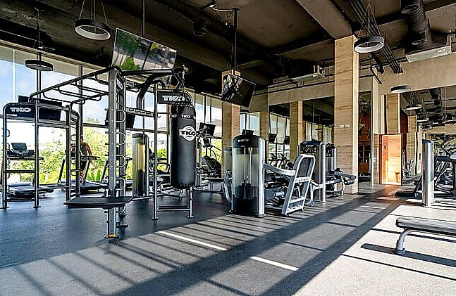 Spacious, air-conditioned fitness center at AWA Playacar featuring strength-training equipment and open workout space, ideal for staying active during your Playa del Carmen vacation
