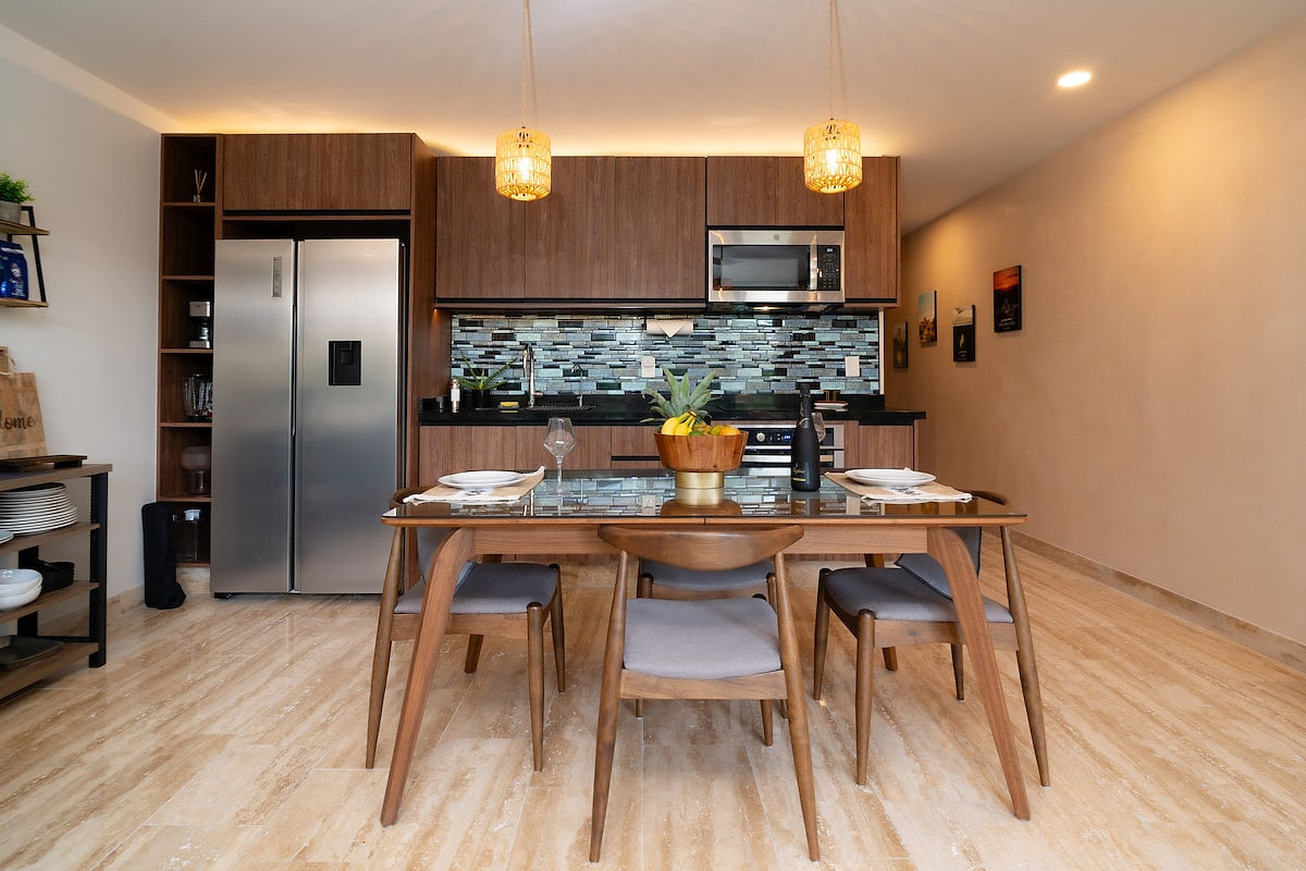 Fully equipped with sleek stainless steel appliances, including a refrigerator, oven, and microwave. The rich wooden cabinetry and stylish backsplash add a touch of elegance to your cooking experience.