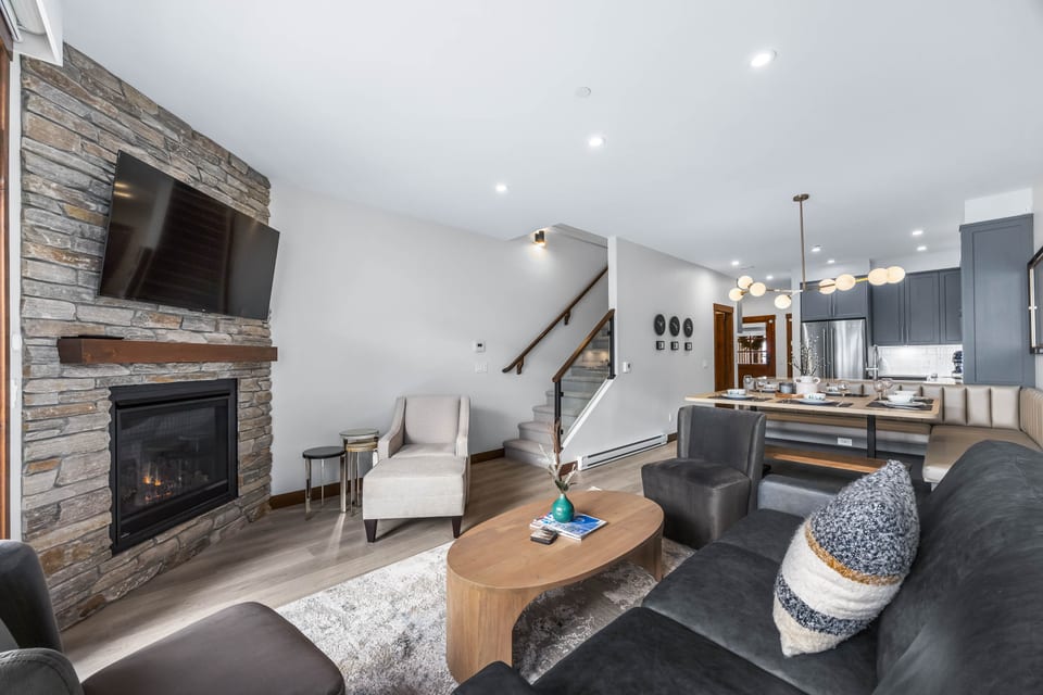 The living room features a 65" smart TV, a gas fireplace, and comfortable quality furniture for gathering with family and friends. 