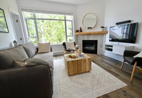 Living Room - The fireplace is tucked in the corner for those cooler nights.  The big window faces east for the morning sun and has a view of the forest and peaks of Blackcomb mountain.Note: Wine & food is staged for illustration (not included)
