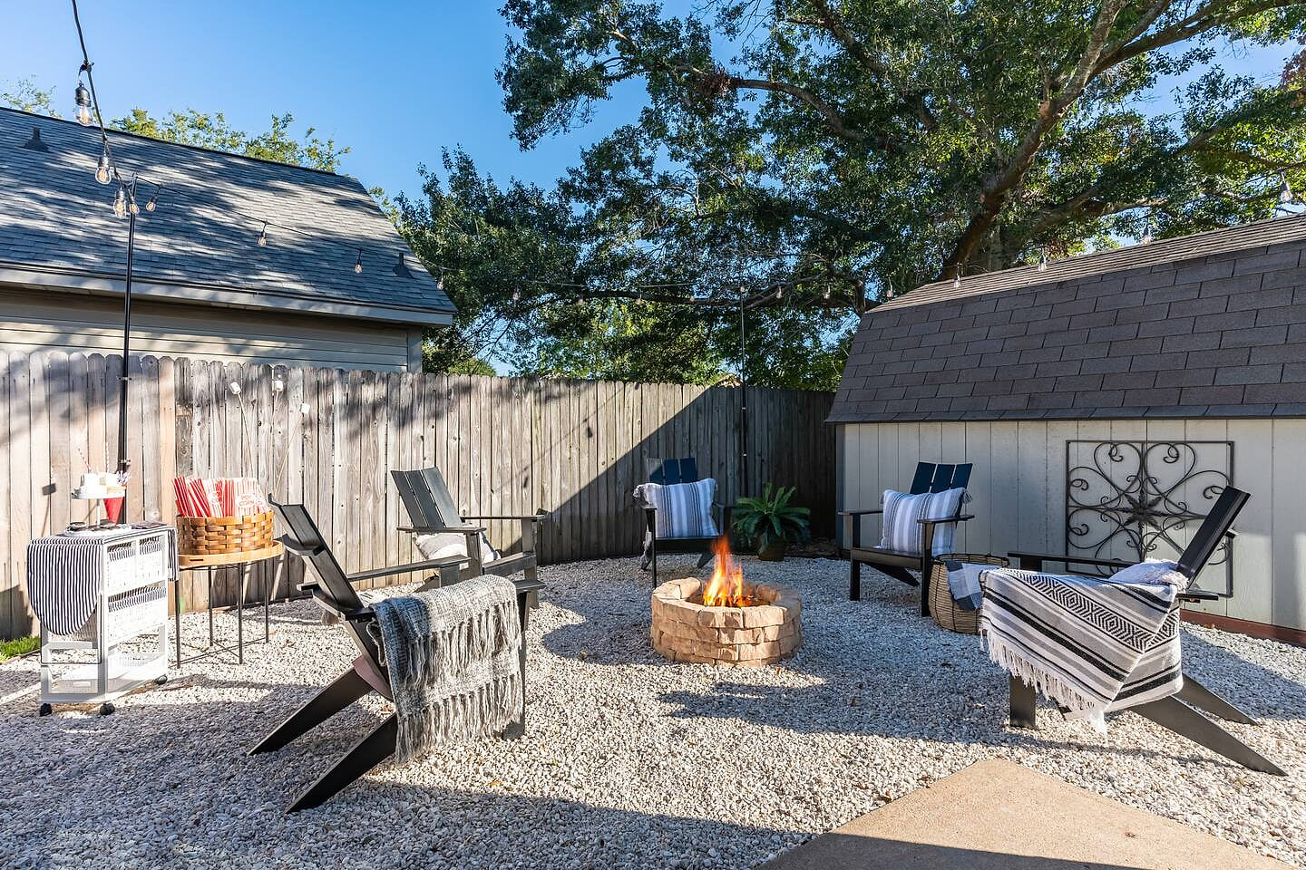 A charming backyard with seating around a crackling fireplace, perfect for enjoying outdoor meals, conversations, or just unwinding