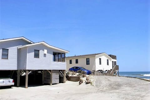 Exterior image of the cottage. The cottage is blue in color. 

Sand is common in the area, including under the house, on walkways, deck, patio, porch and street.